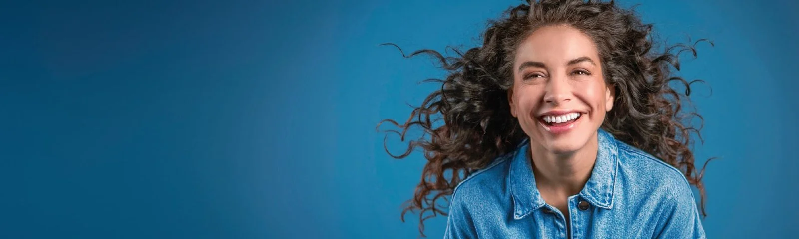 Mujer sonriente con chaqueta de mezclilla y jeans.